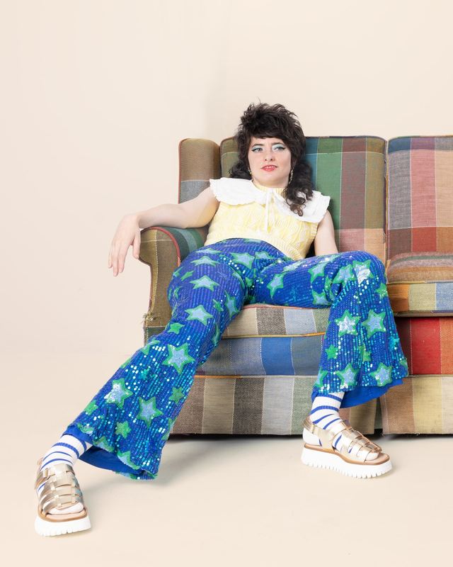 Lounging on a plaid sofa, Sarah Squirm by David Spector
