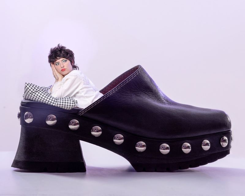 Leaning on an oversized studded clog, Sarah Squirm by David Spector